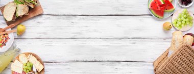 Yaz pikniği yiyecekleri çifte sınır. Beyaz ahşap bir arka plan üzerinde üst görünüm. Piknik sepeti, meyve, salata, sandviç ve atıştırmalıklar. Boşluğu kopyala.