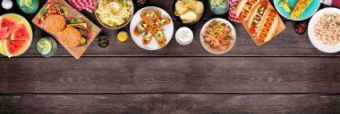 Sosisli, hamburgerli ve kenarlı yaz yemekleri sahnesi. Koyu ahşap bir arkaplan üzerinde üst sınır manzarası. Boşluğu kopyala.