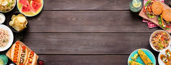 Sosisli, hamburgerli ve kenarlı yaz yemekleri sahnesi. Koyu ahşap bir arka planda üst aşağı çift kenar. Boşluğu kopyala.