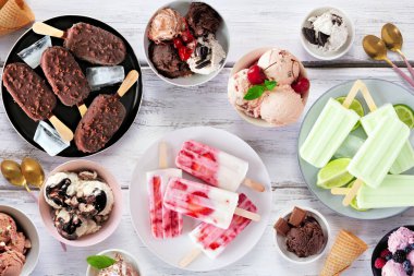 Harika bir yaz yemeği masası sahnesi. Dondurma kaseleri, buzlu dondurmalar ve dondurulmuş ikramlar. Beyaz ahşap arka planda genel görünüm.