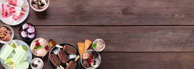 Serin yaz yemekleri köşe sınırı. Çeşitli dondurma kaseleri, buzlu dondurmalar ve dondurulmuş ikramlar. Koyu ahşap arka planda üst manzara. Boşluğu kopyala.