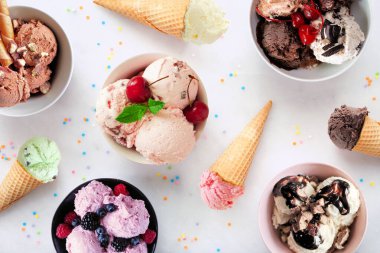 Yaz dondurması masası sahnesi. Rengarenk kase ve koniler. Beyaz mermer arka planda üst görünüm.