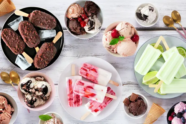 Harika bir yaz yemeği masası sahnesi. Dondurma kaseleri, buzlu dondurmalar ve dondurulmuş ikramlar. Beyaz ahşap arka planda genel görünüm.