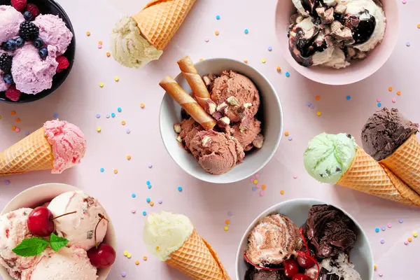Yaz dondurması masası sahnesi. Rengarenk kase ve koniler. Yumuşak pembe bir arkaplanda üst görünüm.