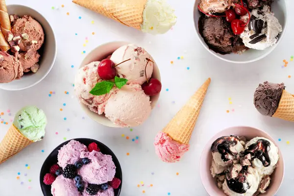 Yaz dondurması masası sahnesi. Rengarenk kase ve koniler. Beyaz mermer arka planda üst görünüm.