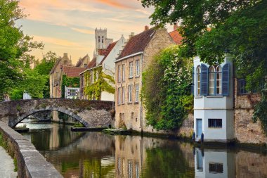 Güzel ortaçağ binaları gün batımında Belçika, Bruges kanallarını kaplıyor.