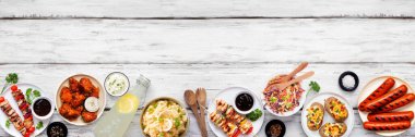Beyaz ahşap bir arka planda yaz barbekü yiyecekleri sınırında. Izgara et, salata ve yanlardan oluşan çeşitlilik. Üst görünüm.
