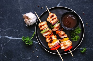 Izgara sebzeli tavuk kebabı. Koyu renkli bir arkaplanda en üstteki tablo sahnesi.