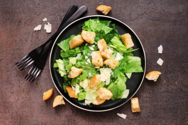 Ekmek arası ve parmesan peynirli klasik Sezar salatası. Koyu bir arkaplanda, görünüm masasının üstünde.