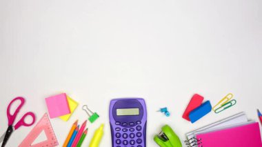 Renkli okul malzemeleri alt sınırdan taşınıyor. Beyaz bir arkaplan üzerinde üst görünüm stop motion loop video. Okul konseptine dönelim..