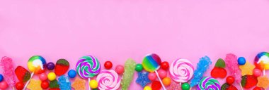 Renkli şeker koleksiyonu. Üst görünüm alt kenarı pembe afiş arkaplanı üzerinde.