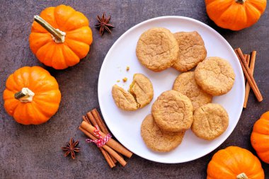Sonbahar balkabağı baharatlı tarçınlı kurabiye tabağı. Masanın üstünde koyu taştan bir zemin var..