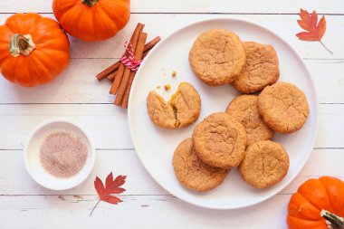 Sonbahar balkabağı baharatlı tarçınlı kurabiye tabağı. Beyaz ahşap zeminli en üstteki tablo sahnesi.