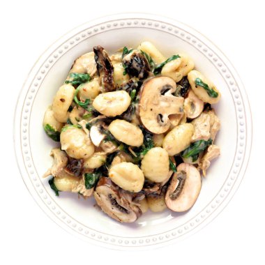 Mantar kremalı Gnocchi, ıspanak, tavuk ve kurutulmuş domates. Üst görünüm beyaz bir arkaplanda izole edildi. Sonbahar yemeği..