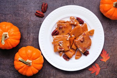 Sonbahar balkabağı, cevizli, kırılgan şeker. Koyu taştan bir zemine karşı tabağın tepesinden aşağı görüş.