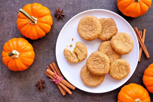 Sonbahar balkabağı baharatlı tarçınlı kurabiye tabağı. Masanın üstünde koyu taştan bir zemin var..