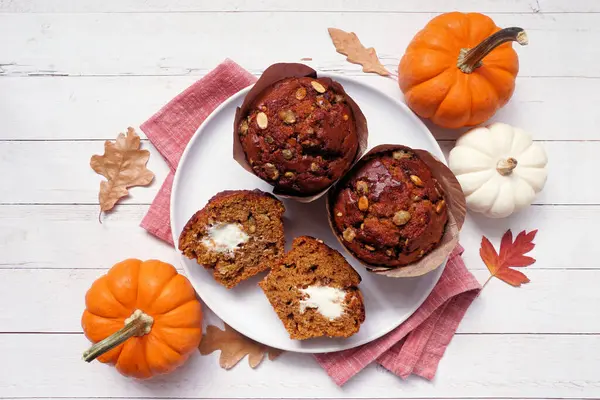 Krem peynir dolu sonbahar balkabağı kekleri. Beyaz ahşap arka planda tepeden aşağı görünüm.