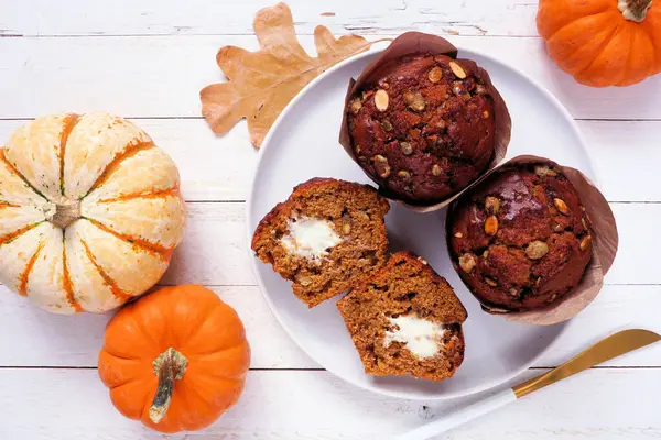 Krem peynir dolu sonbahar balkabağı kekleri. Beyaz ahşap arka planda üst görünüm.