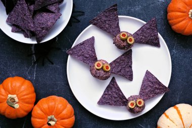 Cadılar Bayramı temalı aperatifler. Mor nachos ile peynir topları ürkünç. Masanın üstünde, koyu renkli bir arkaplan var..