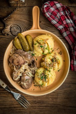 Patates püresi ve salatalık turşusuyla servis edilen soğanlı kızarmış tavuk ciğeri. Küçük bir alan derinliği. Üst görünüm.