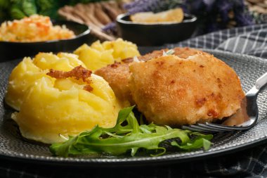 Haşlanmış patates ve sebze salatasıyla servis edilen kızarmış morina filetosu..