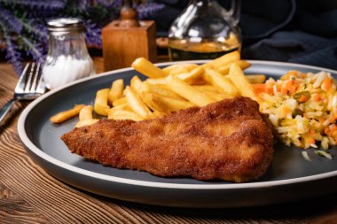 Kızarmış balık fileto, yanında patates kızartması ve salata..