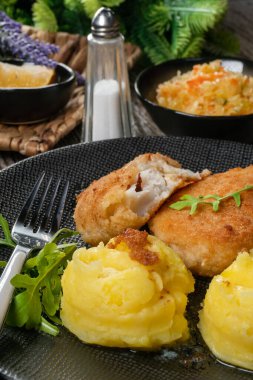 Haşlanmış patates ve sebze salatasıyla servis edilen kızarmış morina filetosu..