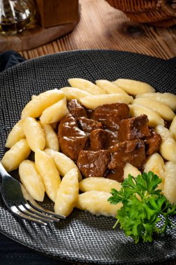 Soslu sığır eti yahnisi, patates köftesiyle servis edilir..