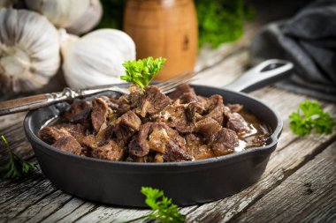 Dökme demir tavada sığır güveci, ahşap arka plan. Sığ alan derinliği.