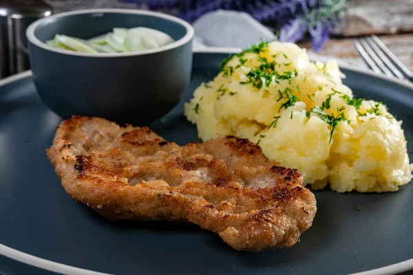 stock image Pork chop served with mashed potatoes and cucumber salad on a dark plate.