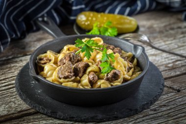 İtalyan makarna kabukları ve biftek sosu ahşap masada dökme demir tavada..