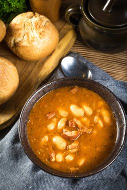 Domates soslu fasulye, pastırma ve siyah kasede sosis. Seçici odak.