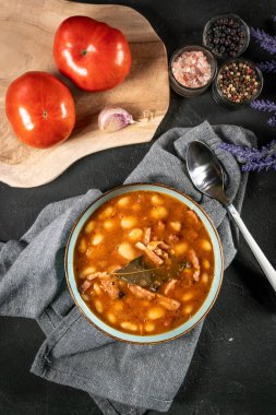 Domates soslu fasulye, pastırma ve siyah kasede sosis. Seçici odak.