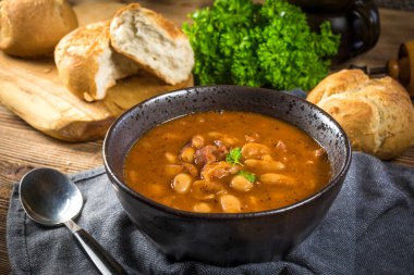 Domates soslu fasulye, pastırma ve siyah kasede sosis. Seçici odak.