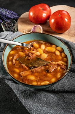 Domates soslu fasulye, pastırma ve siyah kasede sosis. Seçici odak.