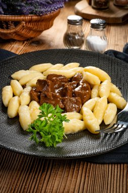 Soslu sığır eti yahnisi, patates köftesiyle servis edilir..