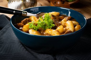 Soslu sığır eti yahnisi, patates köftesiyle servis edilir..