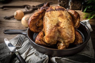 Ahşap masa üzerinde plaka üzerinde kavrulmuş tavuk.