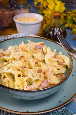 Tagliatelle Carbonara 'yı ahşap masada kasede yosunluyor. Sığ alan derinliği.