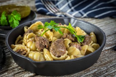 İtalyan makarna kabukları ve biftek sosu ahşap masada dökme demir tavada..
