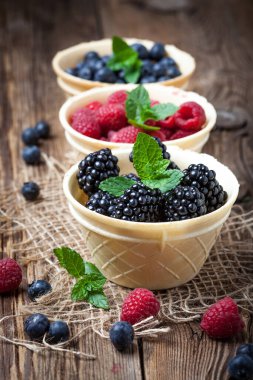 Böğürtlen, ahududu ve yaban mersini bir gözleme içinde kase ahşap bir masaya. Seçici odak.