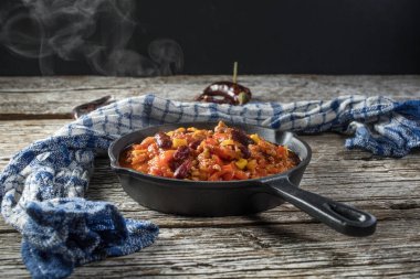 Ahşap arka planda kızartma tavasında Chili con carne. Seçici odak.