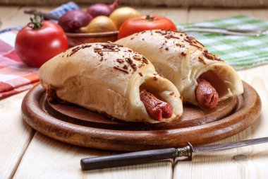 Ahşap bir tahtanın üzerinde hamur içinde pişirilmiş sosis..