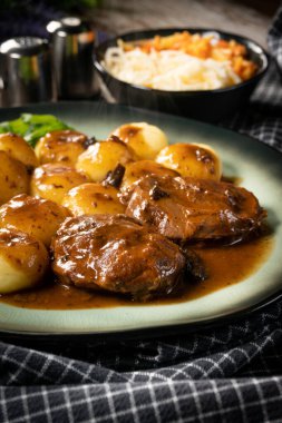 Geleneksel Alman haşlanmış domuz yanakları kahverengi soslu ve mantarlı Silezya köftesi ile servis ediliyor..