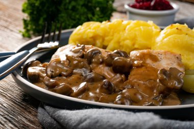 Mantar soslu ızgara tavuk göğsü, patates püresi ve salatalık turşusu ile servis edilir..