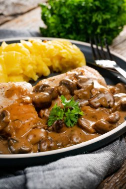 Mantar soslu ızgara tavuk göğsü, patates püresi ve salatalık turşusu ile servis edilir..