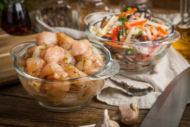 Çiğ tavuk fileto meme parçalar halinde kesilmiş ve cam kapta baharatlı. Küçük alan derinliği.