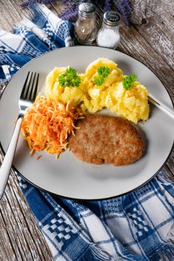 Patates püresi ve havuç salatasıyla servis edilen ev yapımı kıymalı pirzola..