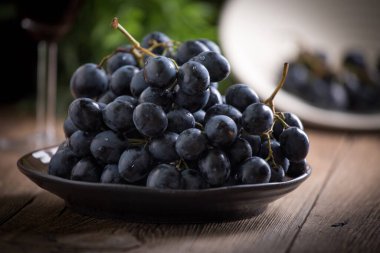 Kara üzüm kase ahşap masa üzerinde. Seçici odak.