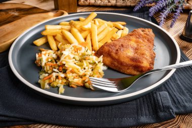 Kızarmış balık fileto, yanında patates kızartması ve salata..